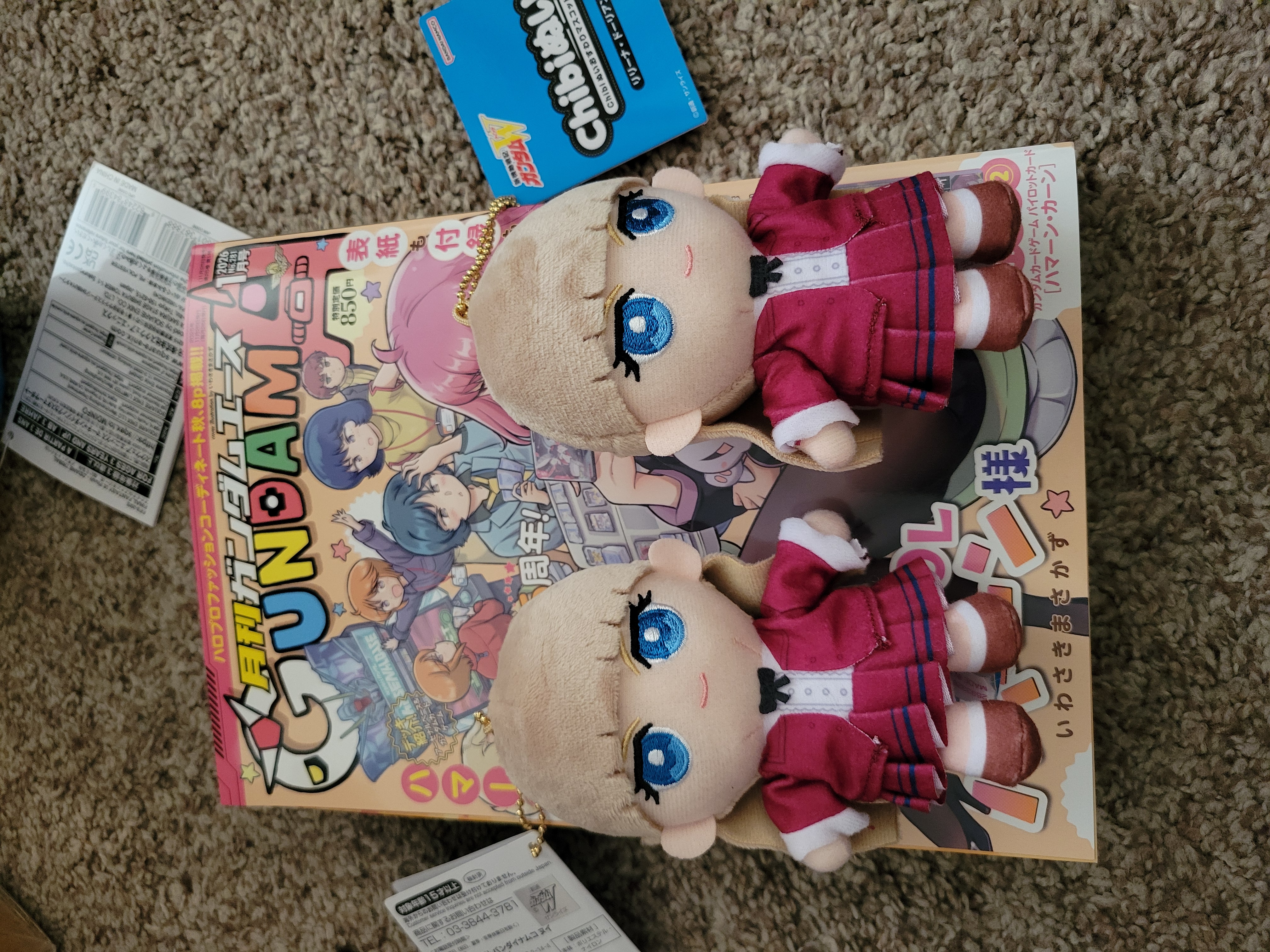 Two Relena plush laying on Gundam Ace magazine.